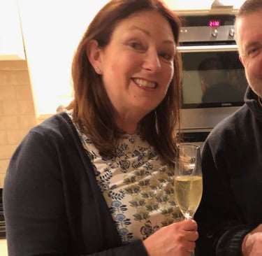 Two adults celebrating birthday in modern kitchen with champagne and cake reading 'Happy Birthday