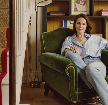 Michelle Dockery sitting in cozy armchair at home.