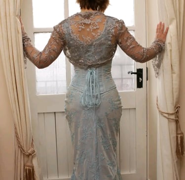 a woman in a blue corset and lace top standing in front of a door