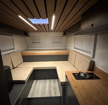 salón interior de una célula camper con luces led, cama y sofas