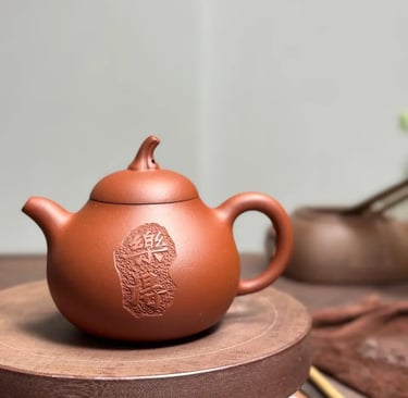 A teapot with engraved text placed on a wooden tabletop