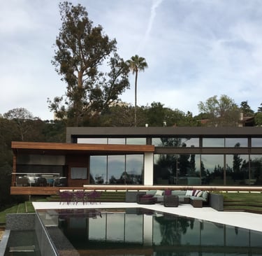 a vanishing edge pool and spa with a view of a large house
