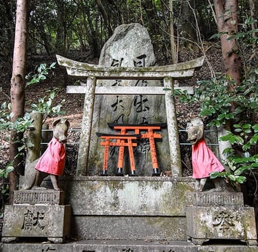 Petit sanctuaire dans la montagne avec des mini portes torii et deux kami renards sur les cotés
