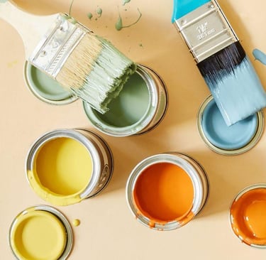 Ekologiczne farby w pastelowych kolorach. Otwarte puszki gotowe do malowania a na nich pędzle