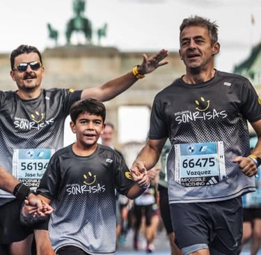 Cuatro corredores de Empujando Sonrisas corren eufóricos con la Puerta de Brandenburgo de fondo