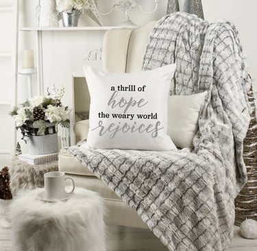 Cozy Christmas home with wing chair & fur throw. Coffee mug. Pillow reads "a thrill of hope the weary world rejoices."