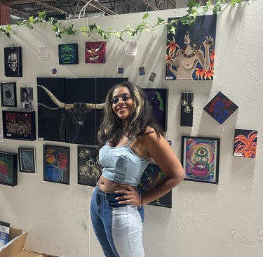 Alexis Peralta the artist standing in front of her wall of art at a gallery tacosxart