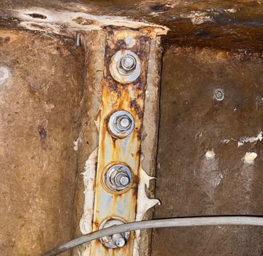 Damaged stainless steel chainplate on the back of a cruising sailboat
