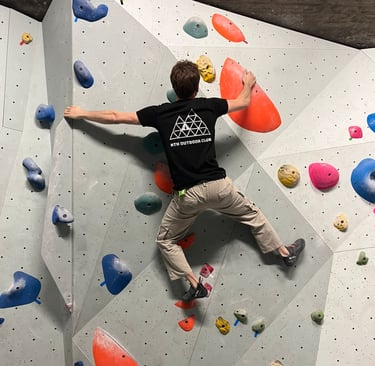 a man is bouldering on a wall in a climbing gym