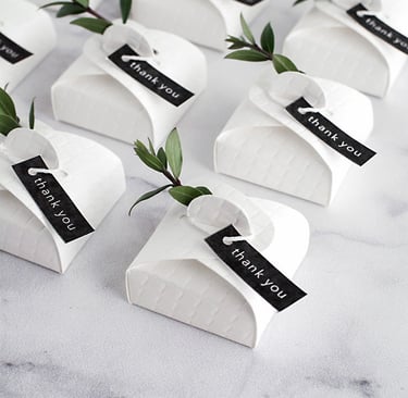 a table with a bunch of small white paper wedding favour boxes