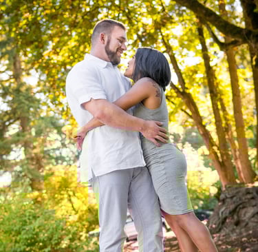 a man and woman standing in front of a tree