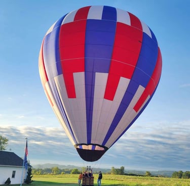 a hot air balloon in a field with people standing around