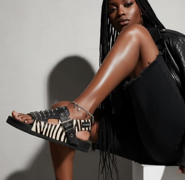 Black woman wearing studded zebra print sandals and a silver anklet for edgy summer fashion.