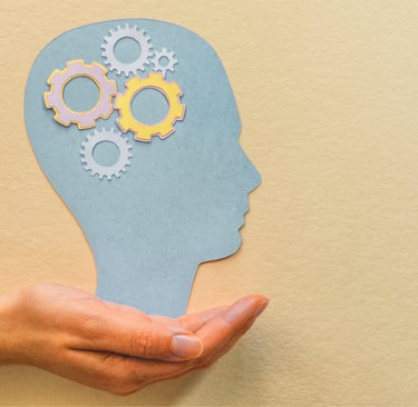 Nell'immagine si vede una mano che sostiene la sagoma di una testa, con degli ingranaggi lavoranti