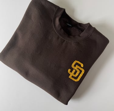 `a brown San Diego Padres sweatshirt with the SD logo embroidered in golden yellow