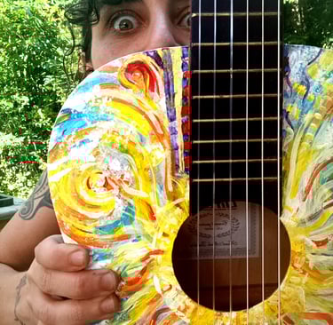 Naia qui tient Suun - une peinture sur guitare très colorée