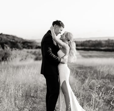a bride and groom kissing in a field