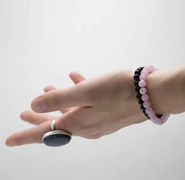 a person's hand holding a rock with a beaded bracelet