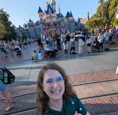 Katie Matzenbacher, standing in front of Sleeping Beauty's castle at Disneyland in California