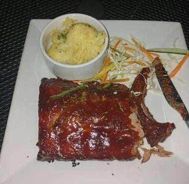 a plate of ribs and mashed potatoes