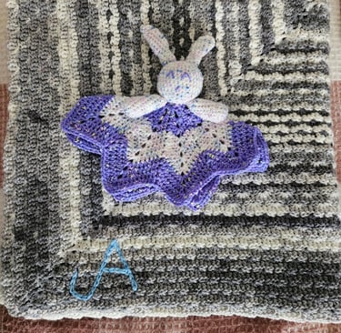 a crocheted rabbit lovey on a crochet blanket