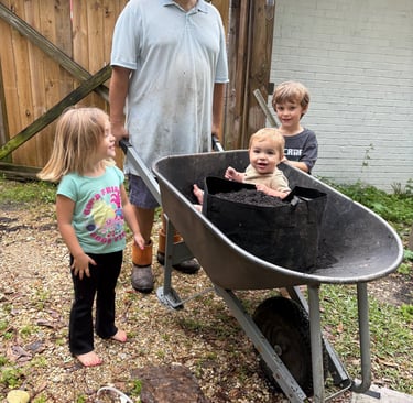 a man and three children in a wheelbarrow