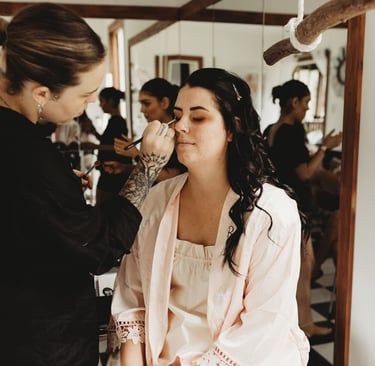 a woman getting her makeup done by a makeup artist