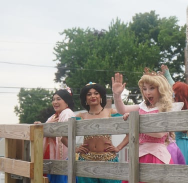 Princesses riding in a parade and waving