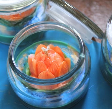 A close-up of a decorative lotus-shaped candle inside a glass jar.