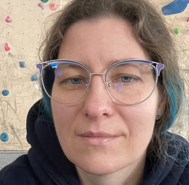 a woman with glasses and a blue hoodie