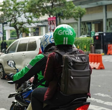 A Grab motorbike rider carrying a passenger on a city street in Vietnam