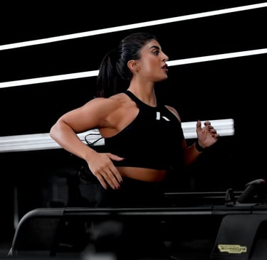 Mais Alhajri running on treadmill in black sportswear inside modern gym with led lights
