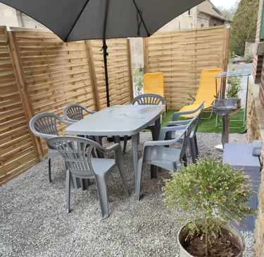 Terrasse ensoleillée avec salon de jardin et parasol. Parfaite pour les repas en plein air. Location de vacances