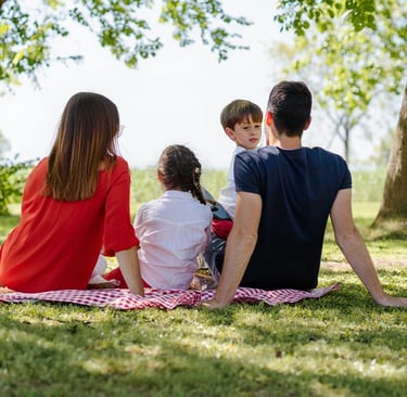 Eine Familie mit zwei Kindern sitzt beim Picknick.