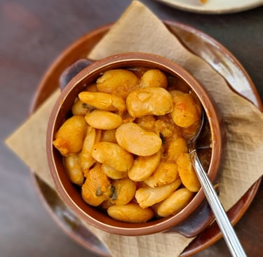 Greek giant beans or Gigantes Plaki served in a traditional clay pot with tomato sauce.