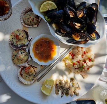Fresh seafood platter with grilled scallops in shells, steamed mussels, ceviche, and lemon wedges.