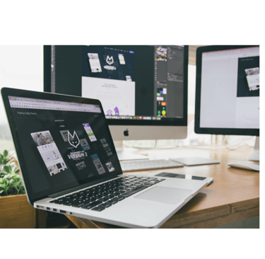A pic of a laptop with two external monitors behind it