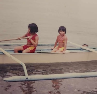 My sister and I on a tropical boat in the water as children.