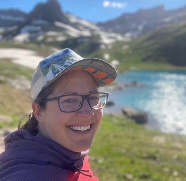Jenna Smiling Outside in a hat by a lake