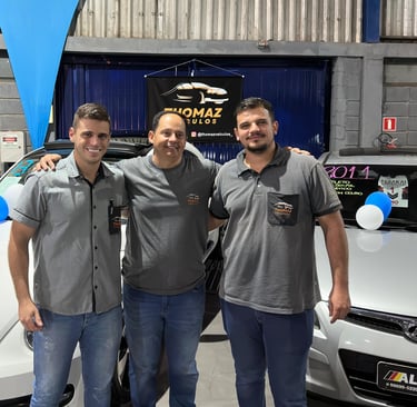 two men standing next to each other in front of a car