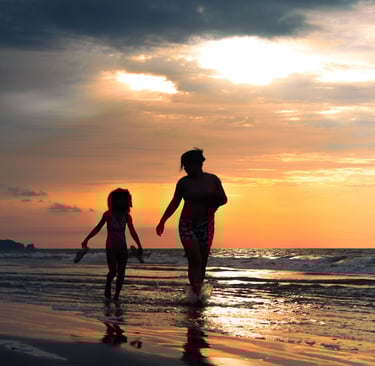 Retrato de una madre y su hija caminando por el agua de la playa en un atardecer