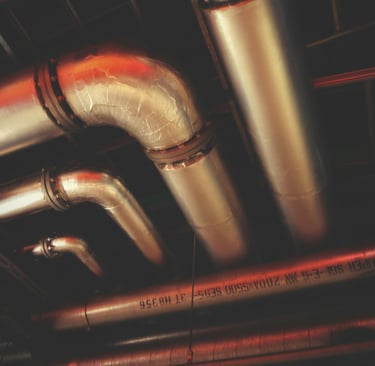 Network of insulated silver pipes on a ceiling.