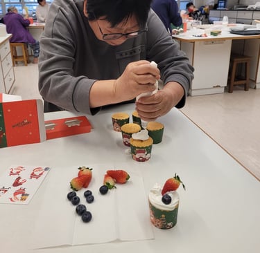 「社福機構長者烘焙班：長者專注練習聖誕 Cupcake 唧花裝飾，透過手作活動訓練手部肌肉並建立自信。」