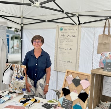 La créatrice derrière son stand sur un marché de créations artisanales