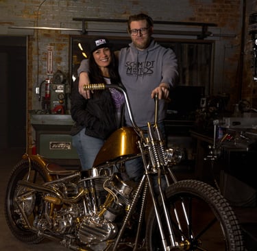 woman and man posing in front of a custom built motorcycle