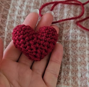 a red amigurumi heart in someones hand