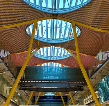 Inside Madrid-Barajas airport Terminal 4, with orange supports holding a wood and glass canopy