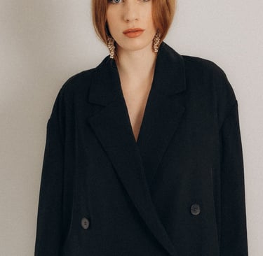 a woman in a black coat and white pants