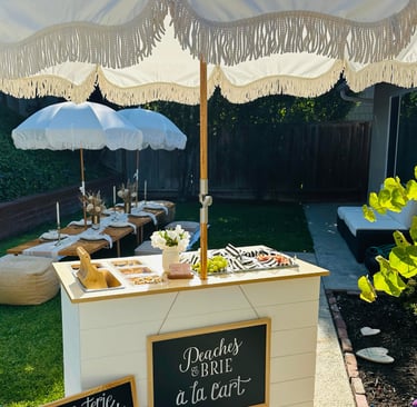 a charcuterie bar cart with umbrella at a party