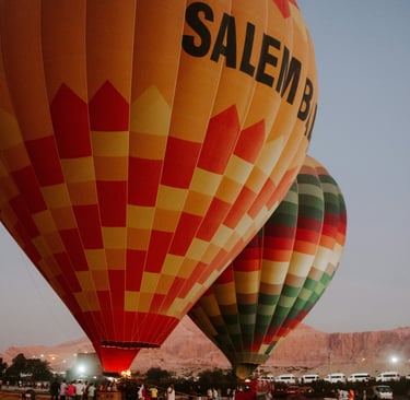 Two colorful hot air balloons floating over the Egyptian desert landscape.